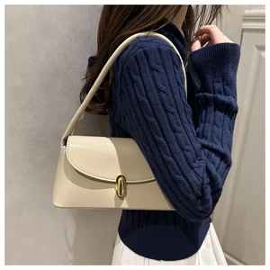 Close-up of beige leather underarm bag with an elegant golden oval twist lock