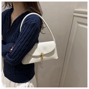 Detail view of cream white patent leather shoulder bag with elegant gold buckle