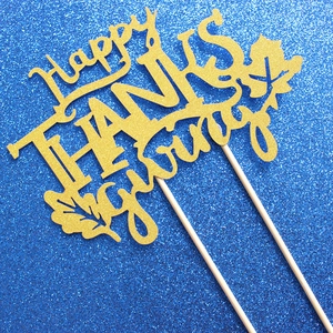 Golden glitter Happy Thanksgiving cake topper with maple leaves on a blue background