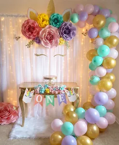 Close-up of unicorn theme first birthday party ONE banner with colorful paper flowers