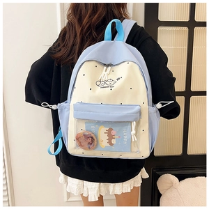 Rear view of a light blue and beige polka dot backpack worn by a model in a room