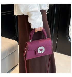 Detailed view of the purple suede surface and floral rhinestone buckle on a handbag