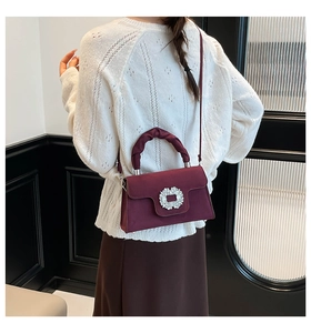 Close-up of burgundy suede handbag with sparkling crystal buckle and pleated handle