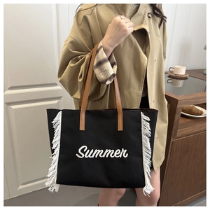 Détail du sac cabas en toile noire avec broderie Summer blanche et pompons décoratifs