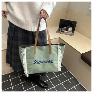 Détail d'un sac cabas en toile vert clair avec des franges blanches et broderie Summer
