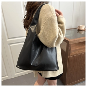 Vista laterale di una grande borsa tote nera in morbida pelle PU indossata da una modella
