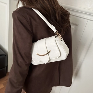 Sac à épaule blanc à motif crocodile avec boucle dorée en croissant porté par modèle