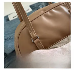 Close-up of silver D-ring hardware and neat stitching on a brown leather shoulder bag