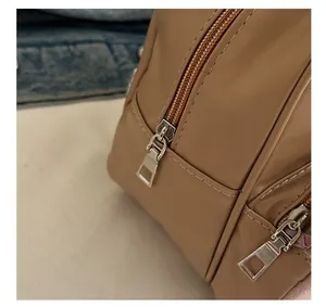 Close-up of sleek dual silver metal zippers on a premium khaki leather shoulder bag
