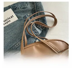 Macro view of tan leather shoulder bag with fine stitching and silver metal link detail