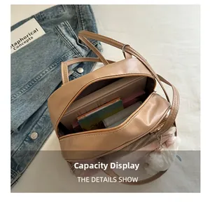 Interior capacity of the khaki cat-shaped backpack with books and a pink fur ball charm