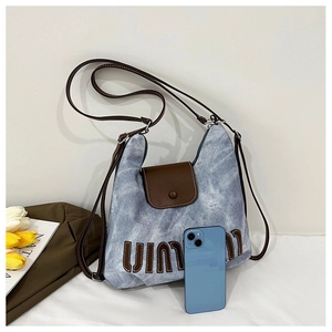 Detail of light blue denim texture tote with brown leather straps and metal snap closure