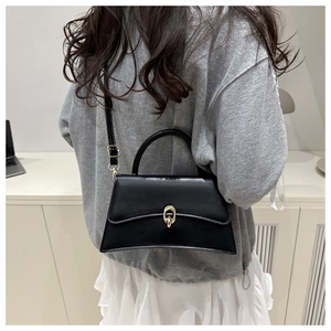 Sac trapèze en cuir noir style français avec base incurvée présenté dans un cadre décontracté