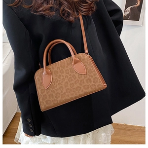 Chic leopard print tote bag with brown leather handles worn by a stylish model