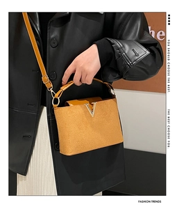 Detailansicht der braunen Wildleder-Beuteltasche mit goldenem V-Beschlag und Handgriff