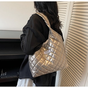 Detail of silver quilted tote bag with diamond stitching and fashion label on shoulder
