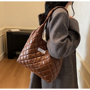 Brown quilted tote bag styled with a grey coat in a minimalist indoor setting