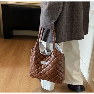 Detailed view of brown quilted puffer tote bag with glossy finish and fashion label