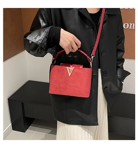 Detail der roten Samthandtasche mit goldenem V-Metall-Dekor und passendem kurzen Griff