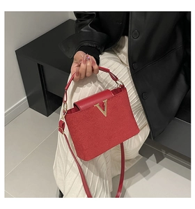 Detail der roten Samthandtasche mit goldenem V-Logo und einer eleganten Lederklappe