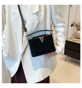 Detail der schwarzen Samt-Handtasche mit goldener V-Schnalle und eleganten Metallbeschlägen