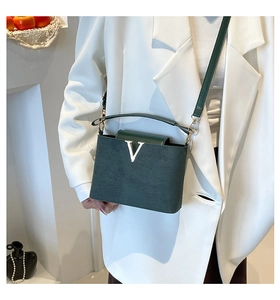 Detail der dunkelgrünen Handtasche mit V-Verschluss aus Metall und weicher Samtoberfläche