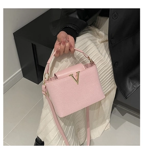 Nahaufnahme einer rosa Eimertasche mit goldener V-Schnalle und verstellbarem Schultergurt