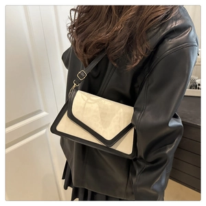 Detail of the high-end rectangular crossbody bag featuring a chic black V-flap and gold hardware