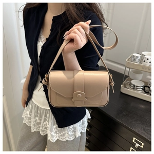 Dettaglio ravvicinato della borsa quadrata in pelle beige con patta e cinturino decorativo