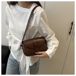 Brown vintage rectangular crossbody bag with flap and decorative buckle on a model