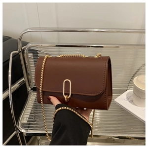 Détail d'un sac bandoulière en cuir marron avec fermoir doré et chaîne vintage