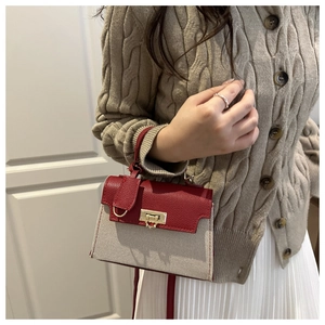 Detail of canvas and red leather contrast handbag with gold clasp on a model