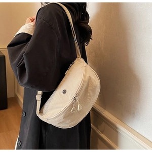 Dettaglio borsa a tracolla in nylon crema con doppia cerniera e logo in metallo