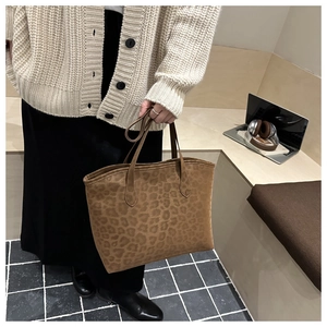 Detailed top view of a large leopard print tote bag with laptops and books in a workspace
