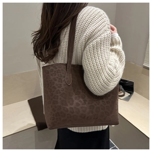 Detail of a deep brown leopard print tote bag with soft suede texture on a beige sweater