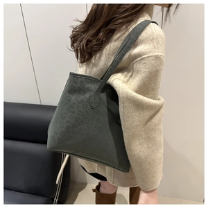 Close-up of a dark green leopard print tote bag with soft suede texture on model