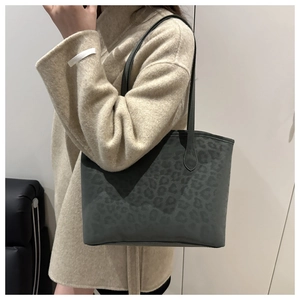 Detail view of large grey leopard print tote bag with black slim handles and matte texture