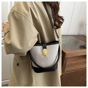 Detail of elegant contrast bucket bag with woven texture and gold metal buckle on model