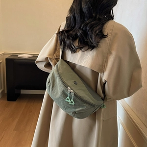 Borsa a tracolla a mezzaluna in nylon verde minimalista abbinata a un classico trench