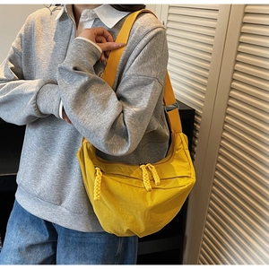 Detailed close-up of yellow hobo bag featuring woven rope zipper and wide strap