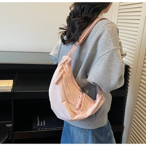 Pink nylon crescent crossbody bag with adjustable wide strap shown in a lifestyle setting