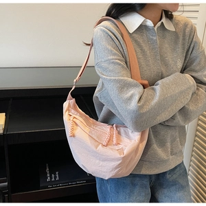 Détail du sac à bandoulière rose en demi-lune avec tissu plissé et tirettes de zip tressées