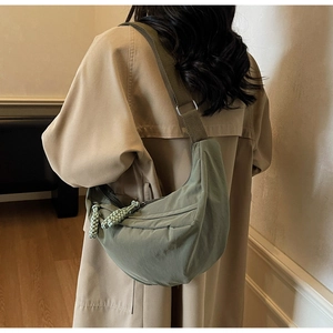 Detail of olive green crescent crossbody bag with adjustable strap and textured nylon fabric
