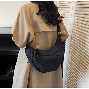 Vue arrière d'un sac bandoulière croissant noir en nylon sur un mannequin en trench-coat
