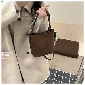 Detail of dark brown suede bucket bag featuring minimalist texture and vintage strap