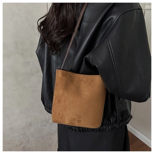 Brown suede bucket bag detail showing soft matte texture and leather shoulder strap