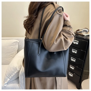 Minimalist black tote bag on shoulder with khaki coat for modern lifestyle look