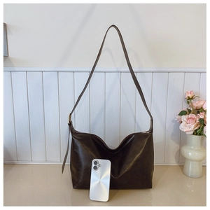 Detail of dark brown leather crossbody bag featuring adjustable strap and spacious interior