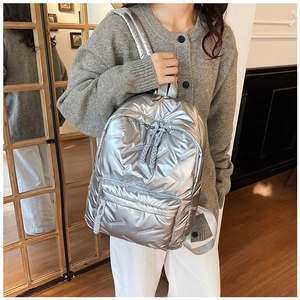 Close-up of a silver quilted backpack featuring a metallic finish and drawstring detail