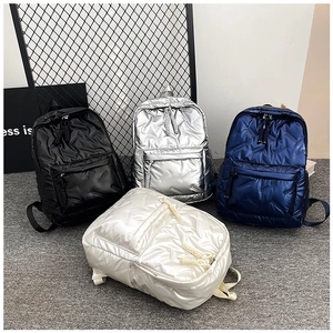 Detailed view of quilted puffer backpacks in black, silver, blue, and white glossy finishes